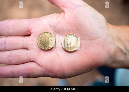 Une main tient deux pièces australiennes de deux dollars : une Reine Elizabeth II de 2017 (par Jody Clark) et un Roi Charles III de 2025 (par Daniel Thorne) à Sydney. Banque D'Images