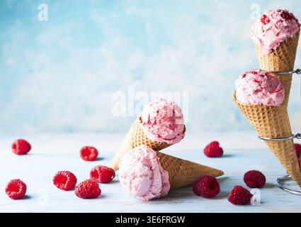 Crème glacée à la framboise dans un cône de gaufrette sur fond bleu Banque D'Images