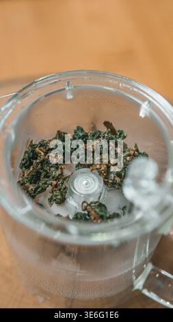 Une vue rapprochée des herbes séchées magnifiquement disposées dans un bol en verre, parfait pour cuisiner ou faire une tisane Banque D'Images