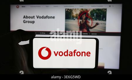 Stuttgart, Allemagne - 08-08-2024 : personne tenant un téléphone portable avec le logo de la société de télécommunications britannique Vodafone Group plc devant l'entreprise webp Banque D'Images