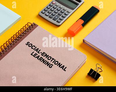 Cahier en spirale avec apprentissage socio-émotionnel écrit sur la couverture, accompagné d'une calculatrice, surligneur, clip de reliure et bloc-notes sur BA jaune vif Banque D'Images