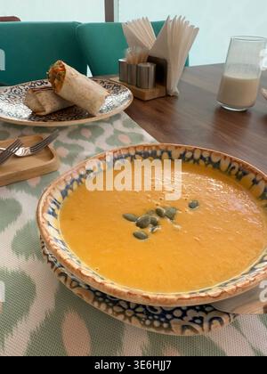 Soupe de citrouille avec des graines de citrouille et des enveloppements sur une table en bois dans un café confortable. Photo mobile Banque D'Images