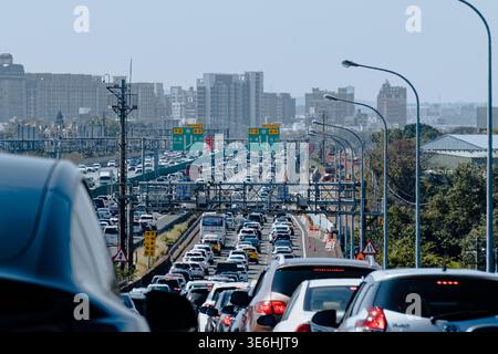 Taoyuan, Taïwan - 11 février 2024 : embouteillages importants sur l'autoroute surélevée pendant la ruée vers le sud de la Saint-Sylvestre lunaire, en raison des gratte-ciel urbains. Banque D'Images