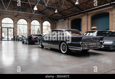 Vue arrière de trois quarts de Facel Vega Excellence dans Classic remise. Rare berline des années 1950 garée parmi d'autres vieux véhicules dans un hall de style industriel. Banque D'Images