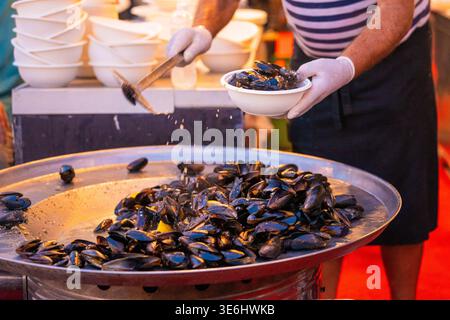 Vue d'un chef servant des moules à la vapeur d'un grand plat en métal, une symphonie culinaire de couleurs et d'arômes, à Pula, comté d'Istrie, Croatie. Banque D'Images