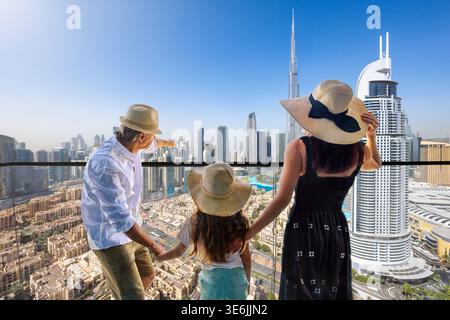 Une famille de touristes profite de la vue panoramique sur les gratte-ciel du centre-ville de Dubaï, Émirats arabes Unis, depuis leur balcon Banque D'Images