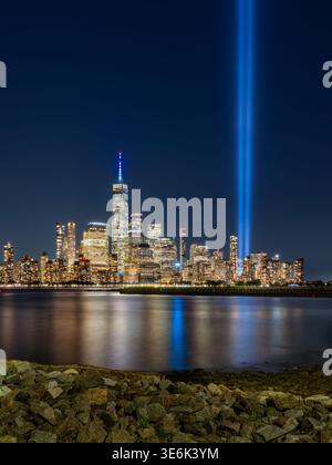 Vue nocturne de New York sur Lower Manhattan avec hommage commémoratif dans des faisceaux lumineux et des reflets sur le fleuve Hudson Banque D'Images