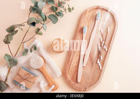 Set de salle de bain écologique avec brosses à dents en bambou, cotons-tiges, savon et brosse en bois sur fond beige. Vue de dessus, pose à plat. Banque D'Images