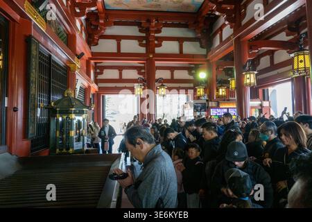 Les visiteurs prient et font des offrandes à l’intérieur du temple Senso-ji à Asakusa, Tokyo, Japon, l’un des sites bouddhistes les plus importants du pays. Banque D'Images