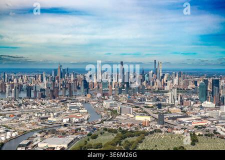 Une vue aérienne large montre le paysage urbain dense du Queens au premier plan avec l'emblématique horizon de Midtown Manhattan Banque D'Images
