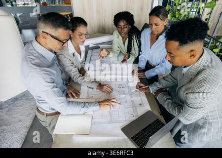 Architectes collaborant sur la table de plan, équipe diversifiée Banque D'Images