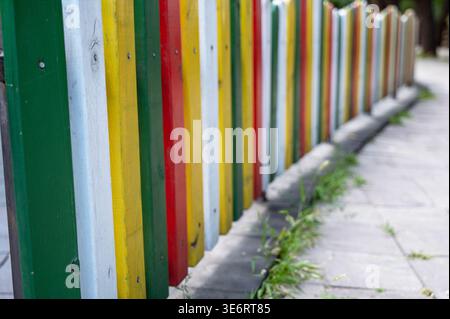 Panneaux de clôture en bois colorés disparaissant au loin. Bois peint brillant en perspective. Concept de design urbain créatif, joie de l'enfance, an Banque D'Images
