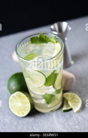 Cocktail de mojito frais avec citron vert, menthe et glace dans le verre sur fond sombre Banque D'Images