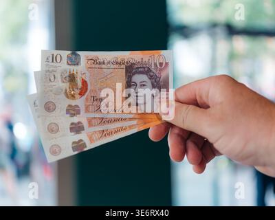 Londres, Royaume-Uni - 20 juin 2025 : vue d'une main tenant de nouvelles notes de dix livres, le papier net reflétant la lumière, un portrait de la reine Elizabeth Banque D'Images