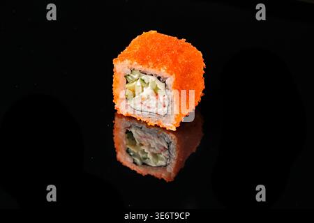 Deux rouleaux de sushi californiens recouverts d'œufs de poisson volants oranges tobiko, avec chair de crabe, fromage à la crème et garniture de concombre, l'un montrant la coupe transversale dans Banque D'Images