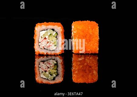 Deux rouleaux de sushi californiens recouverts d'œufs de poisson volants oranges tobiko, avec chair de crabe, fromage à la crème et garniture de concombre, l'un montrant la coupe transversale dans Banque D'Images