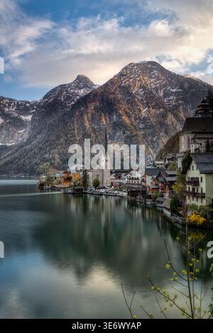 Village de Hallstatt avec son église au bord du lac et les montagnes alpines reflétées dans l'eau calme au lac Hallstatt, Autriche. Banque D'Images
