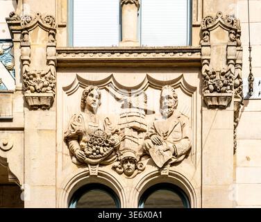 Bas-relief en pierre orné sur une façade de bâtiment représentant une femme tenant un panier de fruits, un homme barbu avec des livres, ornement architectural ci-dessus Banque D'Images