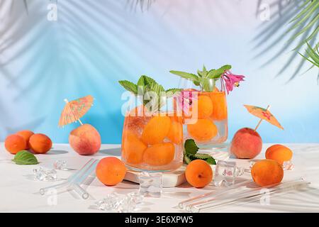 Thé de pêche glacé ou cocktail à la menthe et aux abricots, recette rafraîchissante de boisson estivale. Deux verres avec limonade aux fruits de pêche sur une table lumineuse, régime détox Banque D'Images