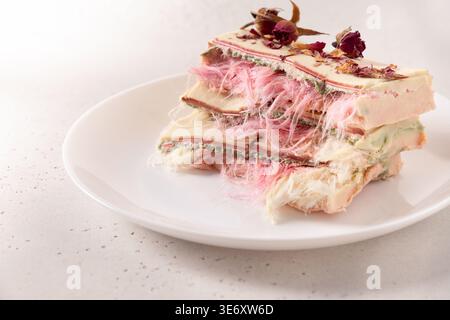 Dessert artistique en couches avec texture aérée de barbe à papa et pétales de rose. Concept de bonbons haut de gamme, design alimentaire moderne, esthétique de beauté et din fin Banque D'Images