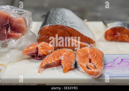 Steaks de saumon frais affichés sur le comptoir dans un marché aux poissons ou poissonnier avec le prix Banque D'Images