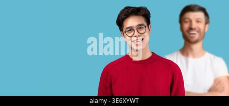 Portrait d'un adolescent asiatique souriant dans des lunettes portant un chandail rouge et posant dans l'espace studio Banque D'Images