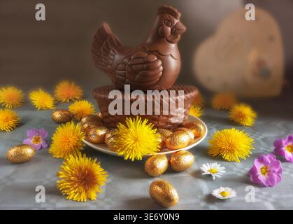 Pont, Côte-d'Or, France - 3 avril 2026 : une composition festive de Pâques mettant en vedette un poulet au chocolat de marque assis sur un panier de chocolat. C'est surro Banque D'Images