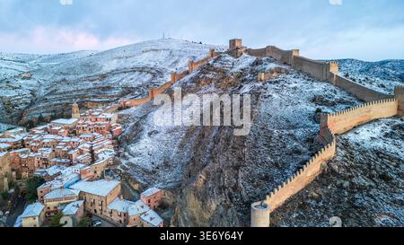 Superbe vue aérienne de Albarracín, Espagne, en hiver. Imposants murs médiévaux escalader la crête rocheuse enneigée, surplombant le village historique avec Banque D'Images