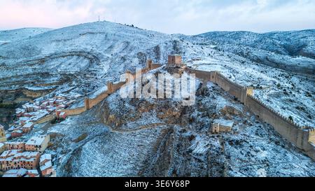 Superbe vue aérienne de Albarracín, Espagne, en hiver. Imposants murs médiévaux escalader la crête rocheuse enneigée, surplombant le village historique avec Banque D'Images