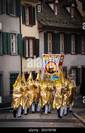 Bâle, Suisse - 10 mars 2025 : vue de personnages dorés défilant à travers le Fasnacht historique, leurs chapeaux pointus et leurs costumes chatoyants Banque D'Images