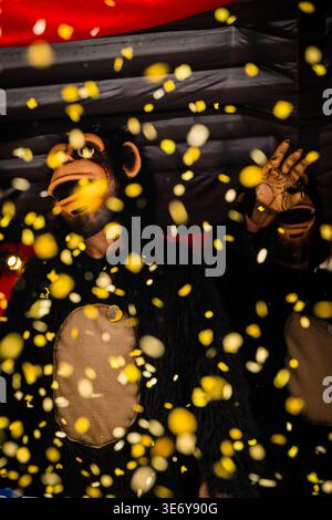 Bâle, Suisse - 10 mars 2025 : vue d'un fêteur costumé au milieu d'une vague de confettis, incarnant le chaos vibrant de Fasnacht. Banque D'Images