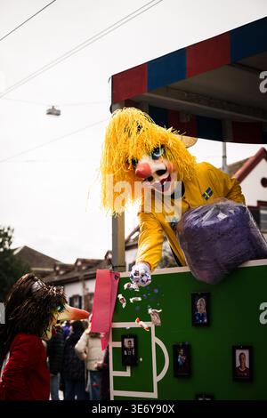 Bâle, Suisse - 10 mars 2025 : vue d'une fête de Fasnacht dynamique avec une figure masquée dans des confettis jaunes jetés d'un char décoré. Banque D'Images