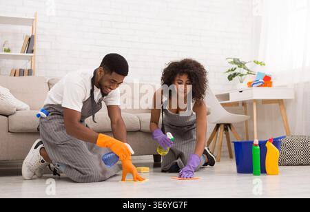 Plancher de lavage jeune couple avec serviette et spray Banque D'Images
