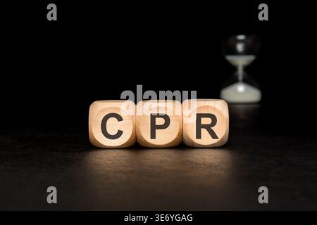 Réanimation cardiopulmonaire CPR acronyme sur blocs de bois avec sablier flou. Urgence médicale et concept de premiers secours. Banque D'Images