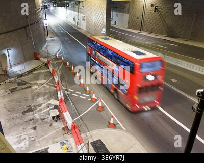 Londres, Royaume-Uni - 8 avril 2026 : les travailleurs en équipement haute visibilité poursuivent les travaux routiers essentiels tard dans la deuxième nuit sur le portail sud du tunnel Silvertown le 8 avril 2026. La bretelle d’accès reste inachevée suite à un important projet de resurfaçage qui a coïncidé avec le premier anniversaire du tunnel. Les sacs de matériaux de construction et d'équipement lourd restent sur place pendant que les équipes travaillent vers l'achèvement. La fermeture en cours a contraint les lignes de bus locales et le trafic A102 à des déviations étroites. Crédit : xiu bao/Alamy Live News. Banque D'Images