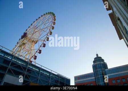 Une vue en angle bas montre la grande roue de Lotte au-dessus du complexe commercial, avec Lotte Cinema et la tour arrondie qui ancre la place à Samsan-dong. Banque D'Images