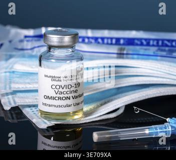 Le vaccin Covid-19 coronavirus a été mis au point pour la variante Omicron avec une aiguille hypodermique avec des masques et de nouvelles seringues en arrière-plan Banque D'Images