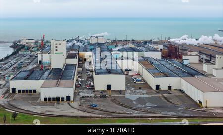 Vue aérienne d'une grande usine industrielle polluant l'air par la mer avec de la fumée Banque D'Images
