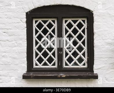 Verre en forme de diamant dans un cadre en bois dans un vieux cottage en pierre peint en blanc Banque D'Images
