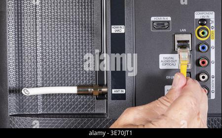 Gros plan de main d'homme caucasien senior branchant Internet dans Smart tv après avoir coupé le cordon de télévision par câble Banque D'Images