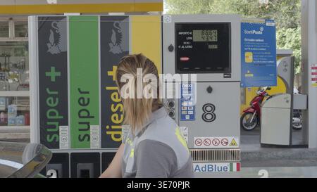 Gardien devant une pompe à carburant avec un affichage des prix pendant la journée à une station-service, Crémone, Lombardie, Italie Banque D'Images