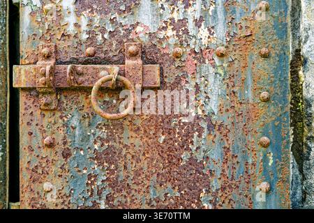 Un loquet rouillé déverrouillé pour une porte en fer corrodée dans un bunker militaire abandonné Banque D'Images