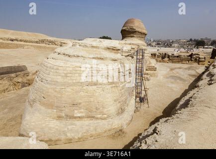 Vue arrière du Sphinx aux pyramides de Gizeh au Caire Egypte avec la ville au loin Banque D'Images