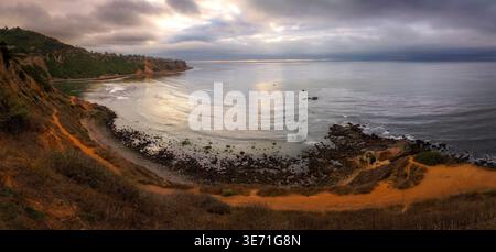 Lumière Golden Hour au-dessus de falaise côtière accidentée et rivage rocheux avec océan calme et ciel nuageux spectaculaire, paysage de la côte californienne Banque D'Images