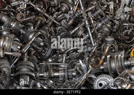 Vue aérienne d'un grand tas d'engrenages métalliques assortis et de pièces automobiles. La collection comprend des arbres, des roulements et divers composants mécaniques Banque D'Images