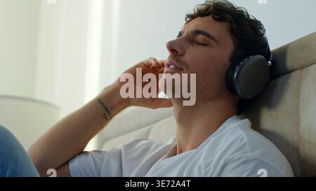 Détendu homme caucasien dans la chambre à coucher à la maison portant des écouteurs appréciant la musique son calme gars masculin se détendre les yeux fermés écoutant la chanson playlist gadget audio Banque D'Images