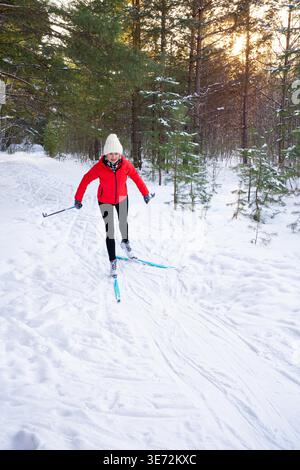 Femme sur le ski de fond dans la forêt d'hiver ensoleillée, espace de copie. Style de vie sain, activités de plein air et concept de fitness hivernal. Des gens actifs heureux. Banque D'Images