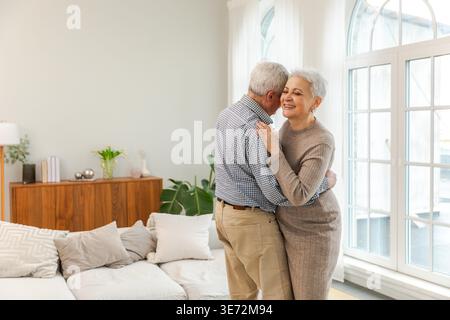 Continuez à bouger. Romantique couple senior mature dansant sur la musique ensemble à la maison. Heureux souriant famille retraité homme femme mari femme ayant du plaisir à profiter du temps ensemble. Moment en famille aime les soins Banque D'Images