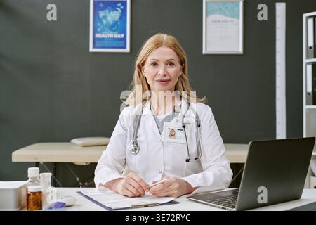 Portrait de médecin féminin d'âge moyen assis dans le cabinet médical Banque D'Images