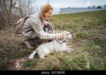 Femme caressant le chien blanc labrador retriever pendant la promenade en plein air Banque D'Images